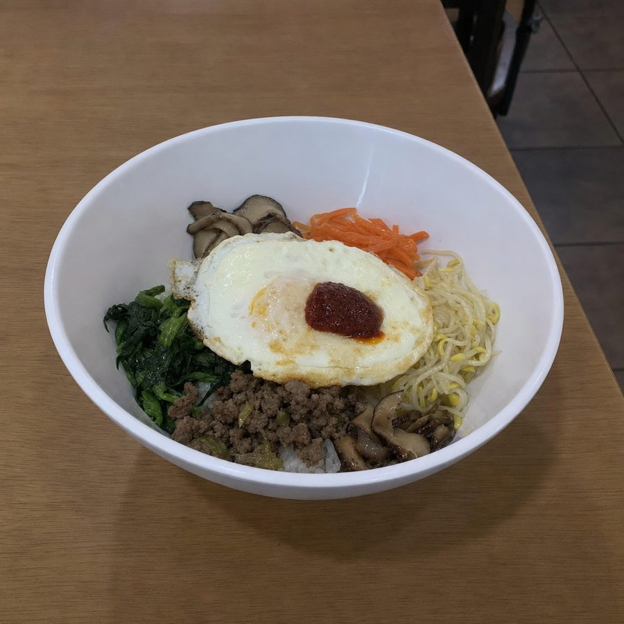 A bibimbap bowl photographed in dull, flat gray light