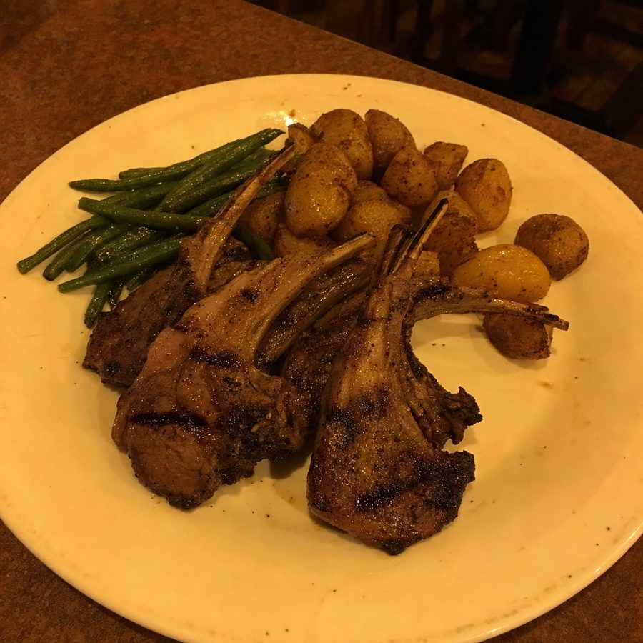 Grilled lamb chops photographed under warm indoor light with a strong yellow cast