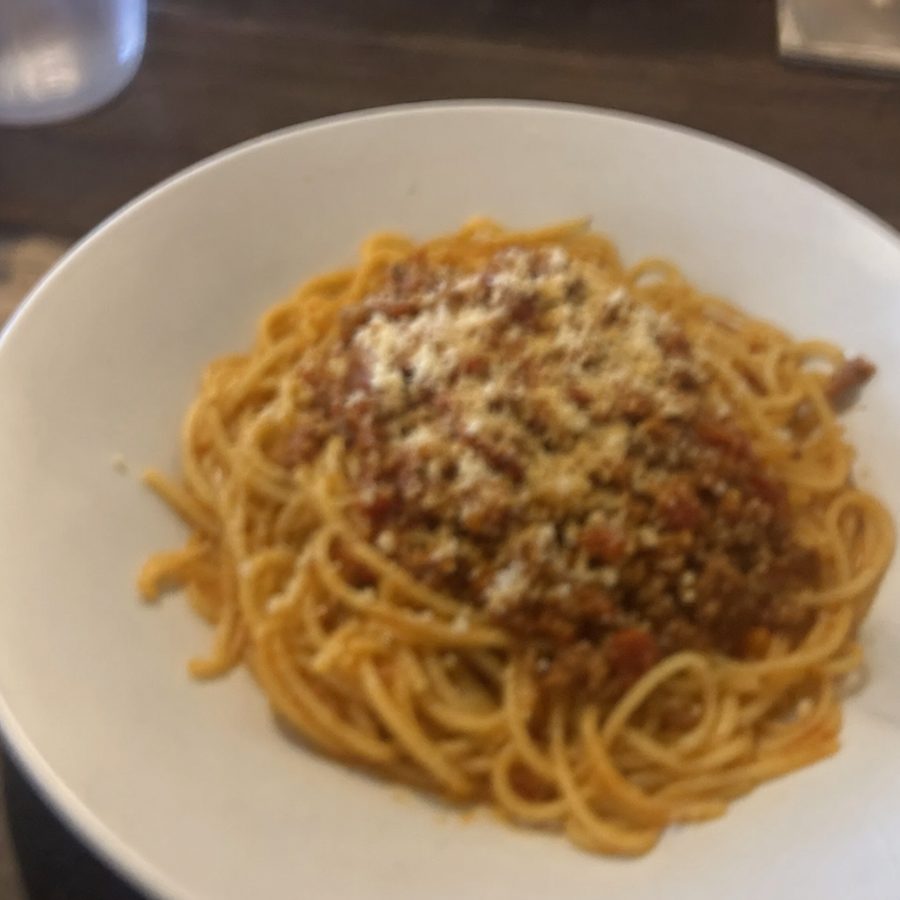 Blurry, out-of-focus phone photo of a bowl of spaghetti bolognese