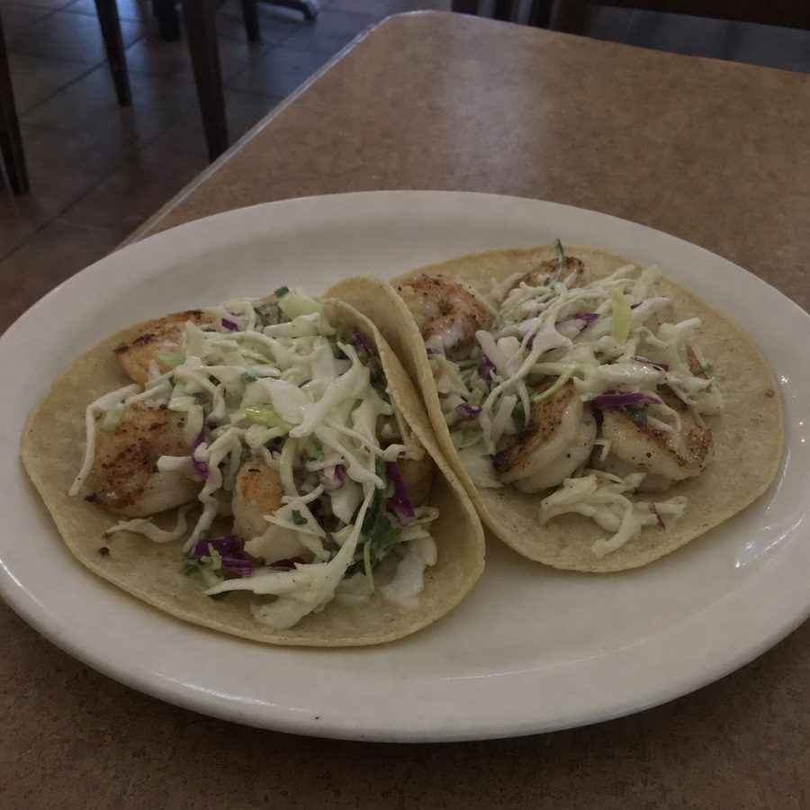 Ordinary flat, dull phone photo of two shrimp tacos on a plain plate