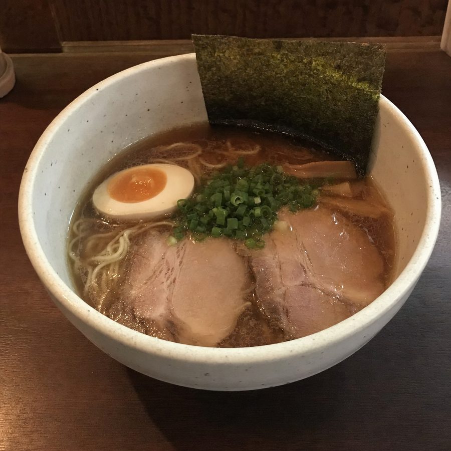 Phone photograph of a ramen bowl in dim, mixed service light before editing
