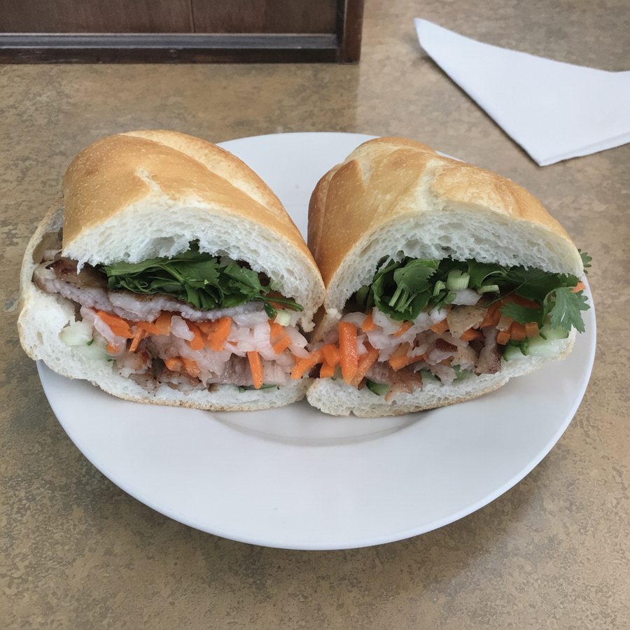 A banh mi shot in washed-out light, then balanced and evened while the pork, pickled carrot and daikon, cucumber, and cilantro in the baguette stay unchanged on the same table