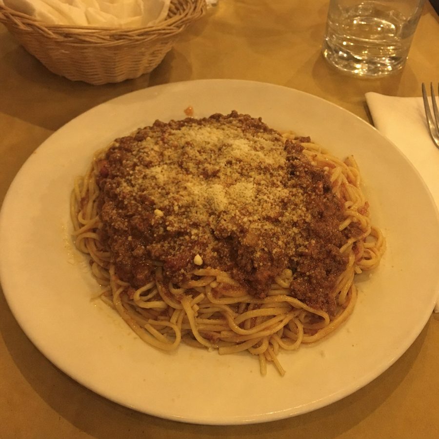 The same plate of spaghetti bolognese before and after: the warm, dim restaurant lighting corrected and brightened, with the spaghetti, meat sauce, and parmesan unchanged on the same table