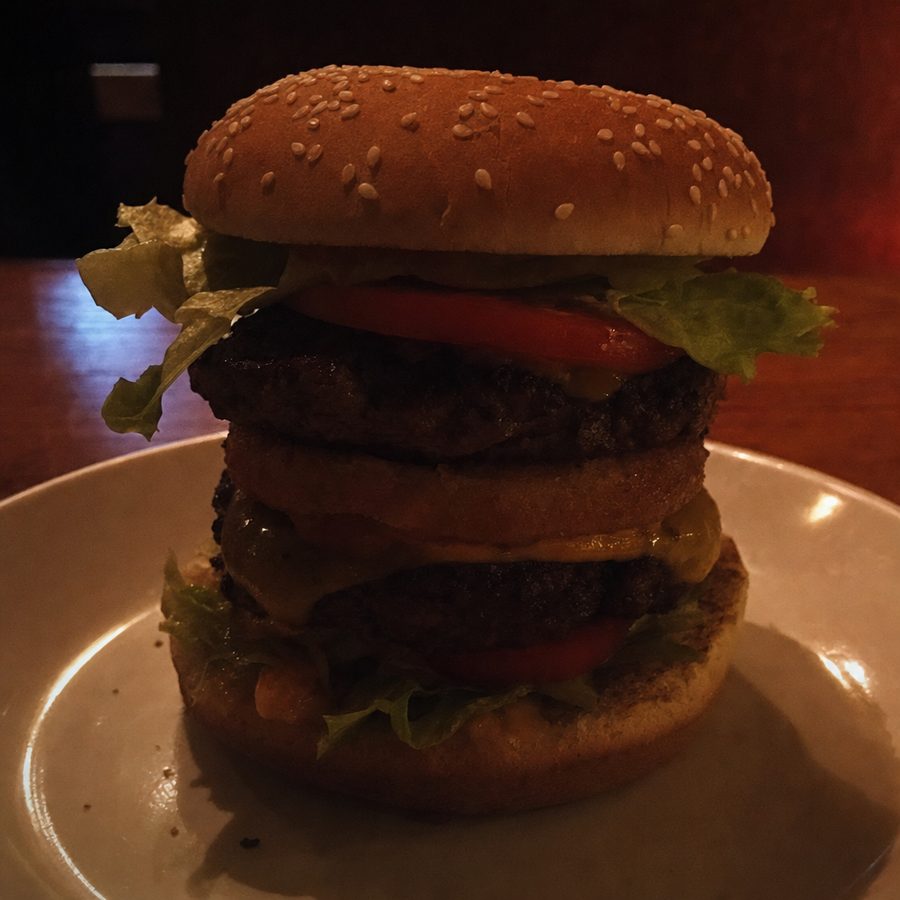 Tall burger in dim warm light with deep shadows hiding its layers